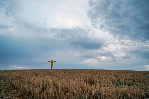 Young woman wearing a yellow raincoat breathes the fresh air