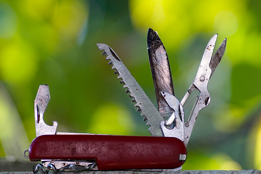 Swiss knife, used, dirty, pictured in nature.