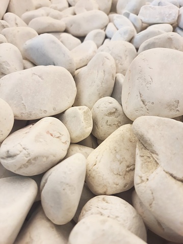 Clean texture of white pebbles. Small stones on the ground. Top view, full screen. Widely used in garden decoration.