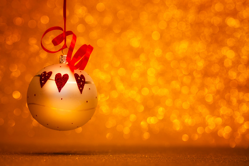 Christmas Bauble with red hearts on golden glitter background