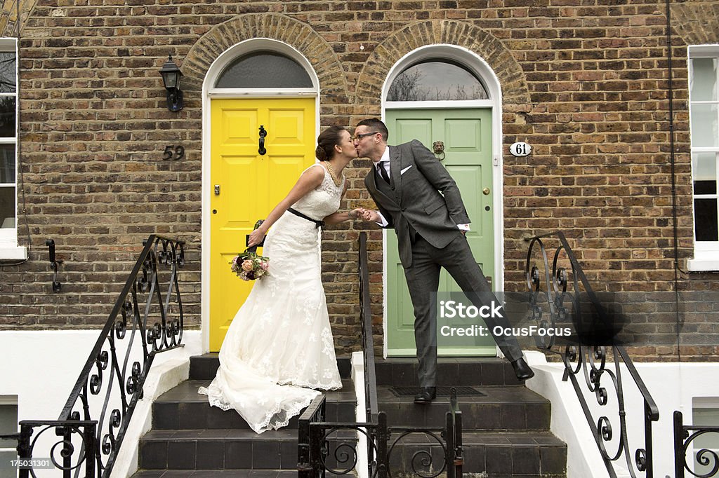 Happy Couple Kissing Happy couple kissing on their wedding day in front of their dream home in London Adult Stock Photo