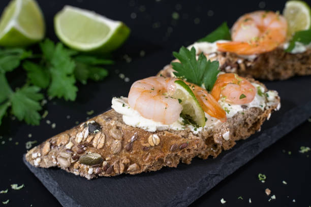 istock Closeup Crispy appetizer with wholemeal bread, spreadable cheese, shrimp and lime 1750314070