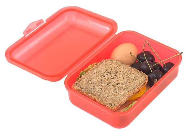 School girl opening her lunchbox that contains a mix of sugary snacks and low quality ingredients such as white bead and potato chips. Colour, horizontal with some copy space.Please see my other pictures in this series illustrating good/bad concepts.