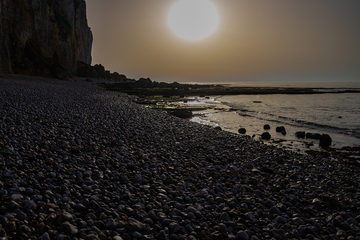 Two crossed feet on the beach facing the turquoise seaside