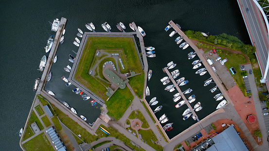 A beautiful harbour with several boats and sailboats parked symmetrically in the Polish town of Kolobrzeg. Taken from a drone from a bird's eye view. Top down seaport traffic