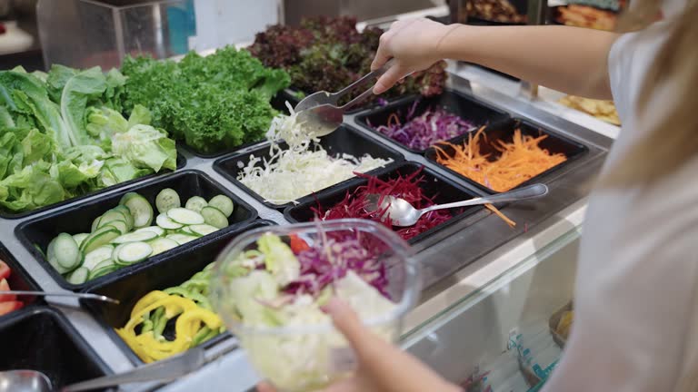 Woman picking vegetables at the salad bar