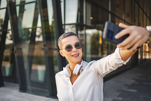 Mature white woman with short hair taking selfies after work