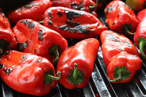 Grilling red bell peppers on barbecue close-up.