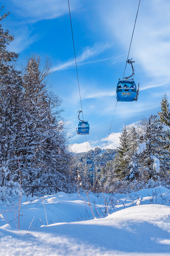 Bansko, Bulgaria - February 3, 2022: Winter resort with ski lift gondola cabins and snow mountains and trees after snowfall