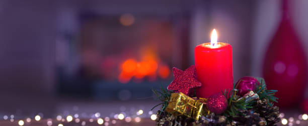 First Advent candles on blurred fireplace background. stock photo