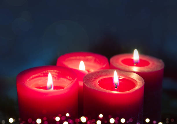 istock Four burning red Advent candles on black background. 1750409038