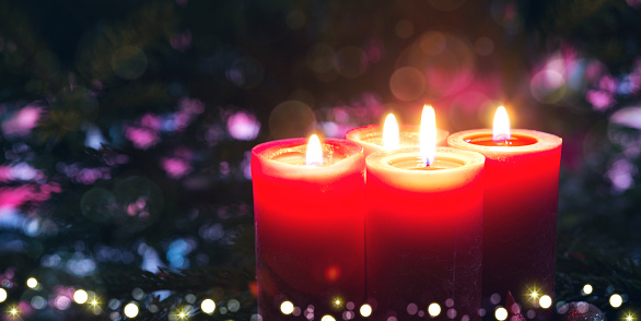 Glowing Advent candles on black blurred background