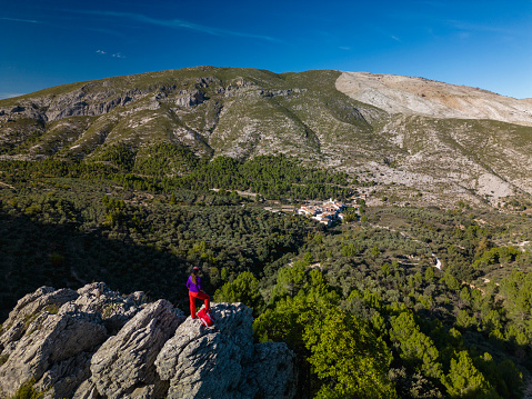 Female hiker looks out above a valley of Famorca village, Costa Blanca, Spain - stock photo