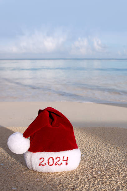 New Year 2024 background with Christmas hat on Caribbean sand. stock photo