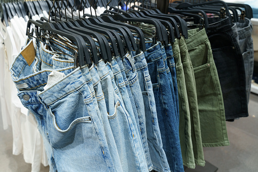 Stylish denim shorts in blue, green and black on a store window. Close-up, background.