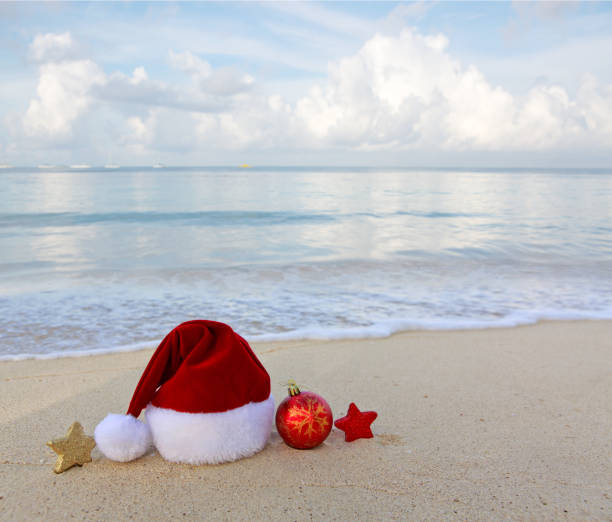 istock Merry Christmas background with red hat and decorations on Caribbean sand. 1750433334