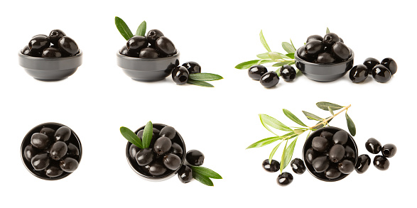Tasty black olives  on  background. Olive and olive tree branches on a white table. Delicacy.