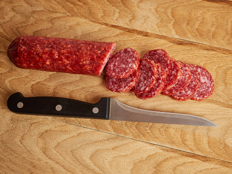 Cut the sausage with a knife on the board. Work in the kitchen.