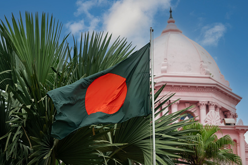 National flag of Bangladesh with the dome of Ahsan Manzil palace in the background.