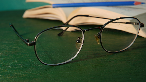 glasses with an open book in the background. educational and business themes. concept of learning, reading books. student theme, homework