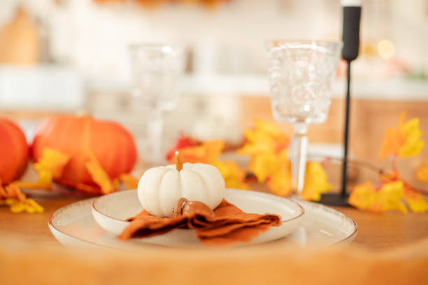 istock Autumn kitchen interior. Red and yellow leaves and pumpkins on a light background. Serving the dinner table 1750515837