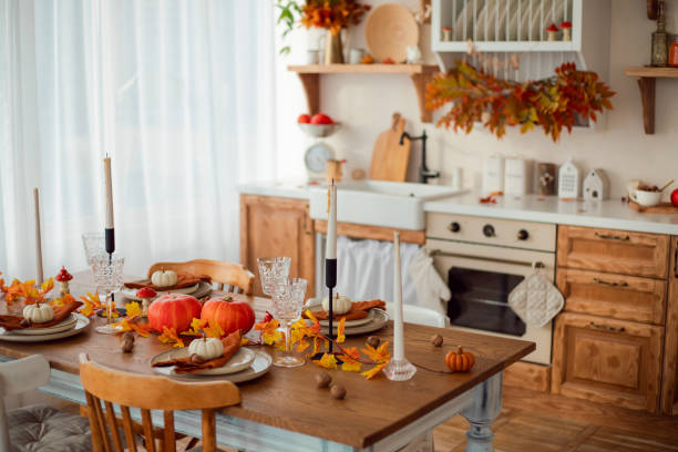 istock Autumn kitchen interior. Red and yellow leaves and pumpkins on a light background. Serving the dinner table 1750516749