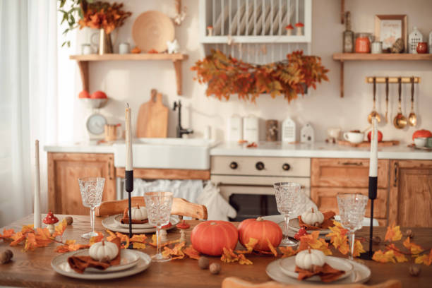 istock Autumn kitchen interior. Red and yellow leaves and pumpkins on a light background. Serving the dinner table 1750516962