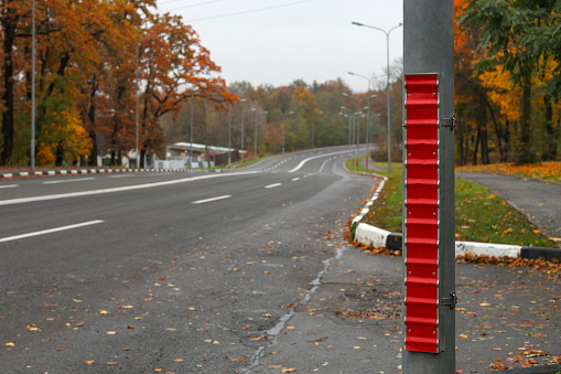 A red reflective strip on a traffic pole located on the right side of the road.