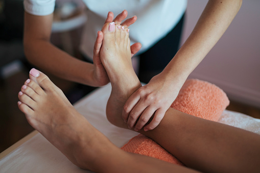 Medical massage at the foot in a physiotherapy center. Female physiotherapist inspecting her patient.