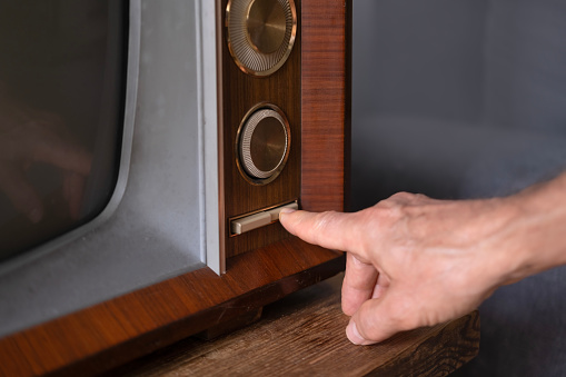 male Hand turns on TV power button, adjusts volume control old retro analog TV, entertainment, Technologies of Past Decades Nostalgia, leisure essential life older individuals, Technology 1960-1970