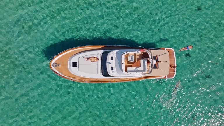 AERIAL High above a yacht and people swimming around it in sunshine