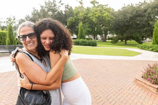 A senior Puerto Rican woman in her 70s greeting her granddaughter in her 20s with a hug in Winter Park, Florida.