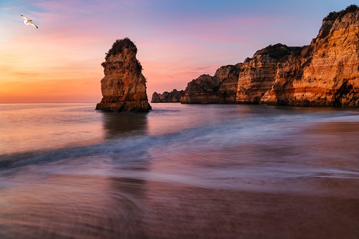 A breathtaking sunset view of two rocky cliffs in the ocean in Algarve, Portugal