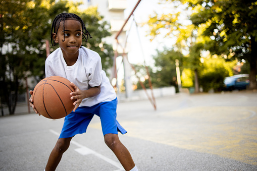 Latin American boy playing basketball at the outdoor basketball court.