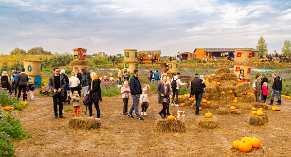 Gdansk, Poland - October 22, 2023: Traditional village harvest festival and Halloween celebration.  People buying ripe autumn pumpkins and walking among colourful haystacks