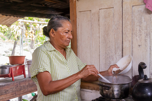 Cacao Chocolate Trip Experience: An old female latin america farmer cooking a hot chocolate with the cocoa pods just harvested in a cacao plantation greenhouse in Latin America.