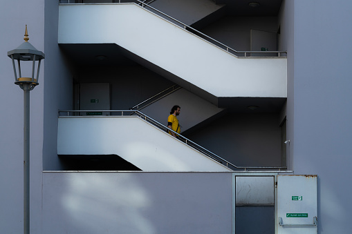 View of man descending the exterior stairs of the building. The door opening to the street and the street lamp can be seen. architectural themed photo. Taken in daylight with a full frame camera.