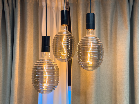 Beautiful lamps with retro lightbulbs hanging in front of curtains