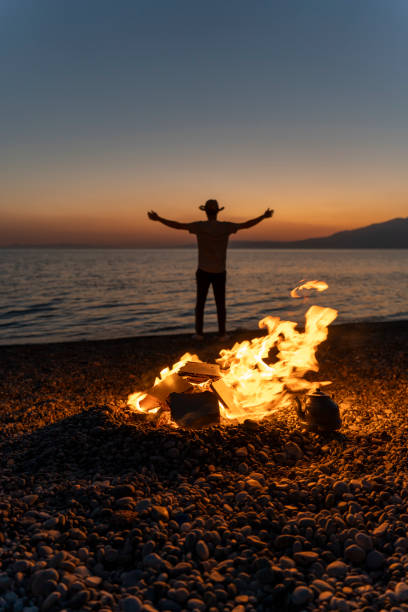 Young people camping by the sea. Enjoying camping at sunset. Tent and campfire.