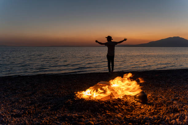 Young people camping by the sea. Enjoying camping at sunset. Tent and campfire.