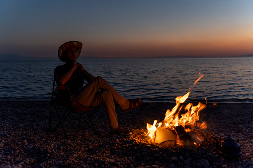 Young people camping by the sea. Enjoying camping at sunset. Tent and campfire.