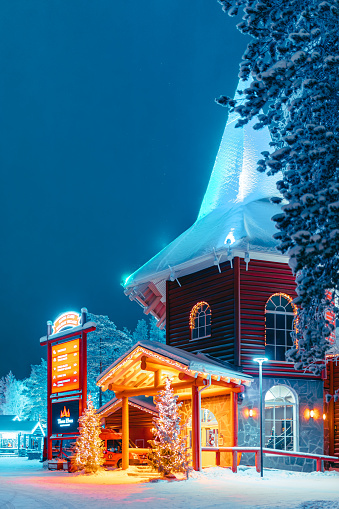 Local people and tourists visit Santa Claus Village (Joulupukki) amusement park, Arctic Circle, Santa's Office, and House of Snowmobiles at night in Rovaniemi in the Lapland region of Finland. It was opened in 1985