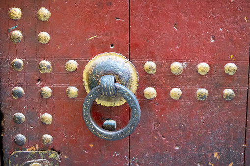 Red antique Chinese doors with brass lion head door knockers and gilded studs.