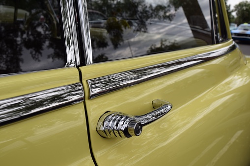 Fresno, United States – October 15, 2023: Photo of a Classic car Yellow Oldsmobile car of the chrome door handle