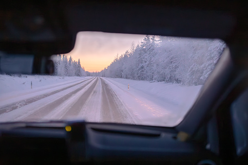 A breathtaking point of view (POV) photo capturing the pristine beauty of Lapland, Finland on an icy-cold day. The snow-covered roads and trees create a magical winter landscape as seen through a car window. Lapland, Finland, Snowy, Winter, Icy-Cold, Snow-Covered, Roads, Trees, POV, Car Window, Winter Landscape