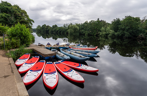 paddleboards and canoes tied up along the River North Tyne at Chollerford, Northumberland, UK