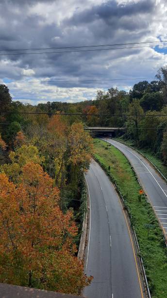 istock Aerial view of a two-way highway, fall colored trees, and a grey sky 1751038392