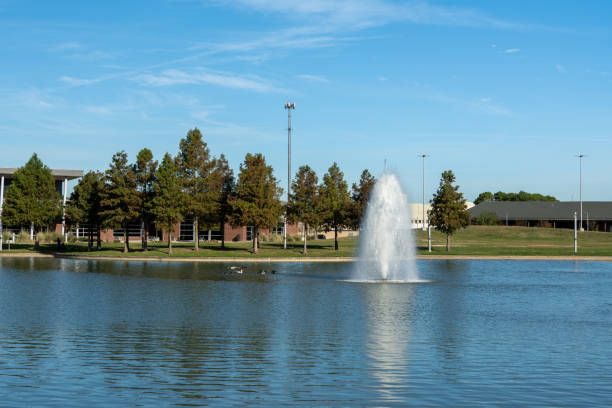 Beautiful Water fountain in a lake Beautiful Large Water Fountain in a lake with water birds swimming around and a blue sky in the background in Beaumont, Texas. beaumont tx stock pictures, royalty-free photos & images