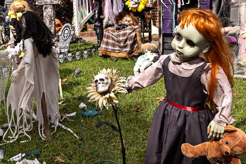 Halloween yard with highlight being a spooky doll holding a teddy bear