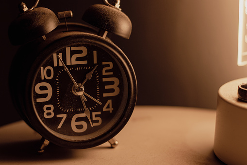 Close-up of a black alarm clock at 01:00 AM, early morning